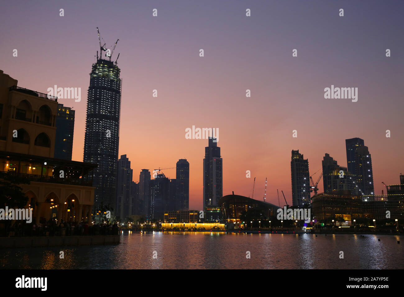 Downtown in the city at sunset with all the skyscrappers illluminated and reflecting in the lake, Dubai, United Arab Emirates. Stock Photo