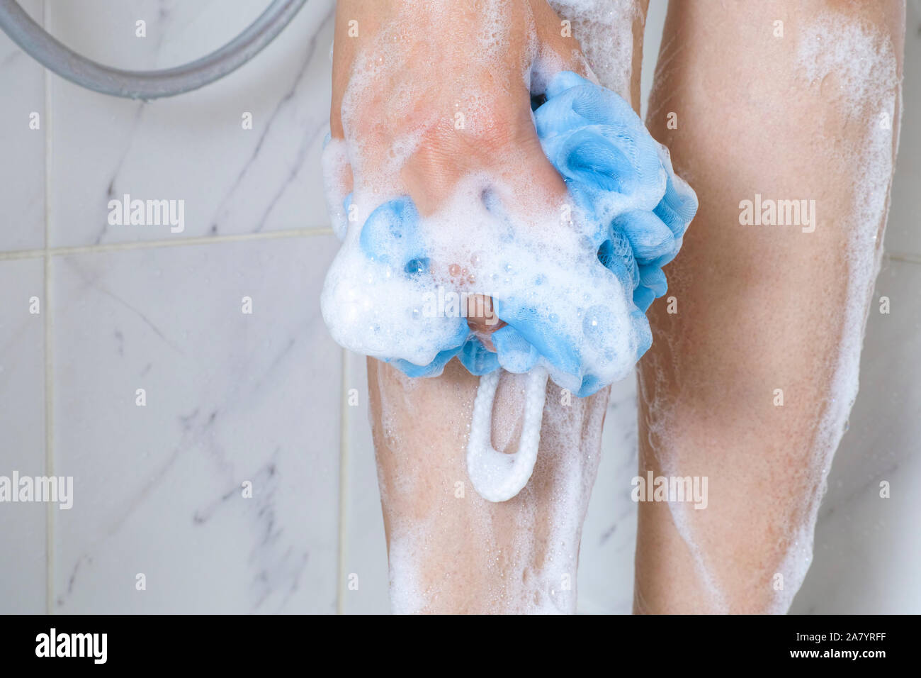 Woman in  foam with sponge washing legs in shower bath. Stock Photo