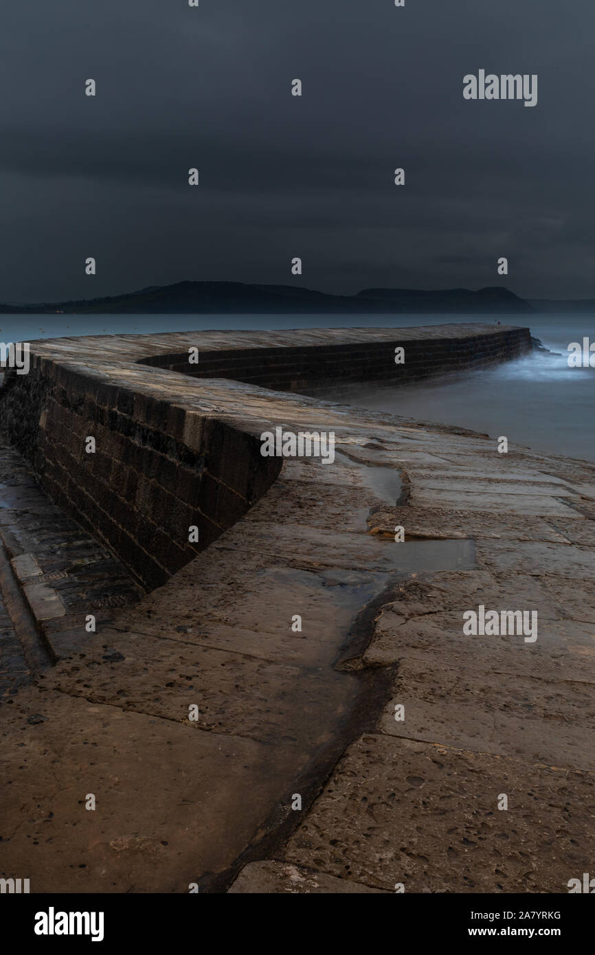 Lyme Regis Dorset England Dawn at The Cobb, the historic harbour wall of Lyme Regis, during stormy, rainy weather Stock Photo