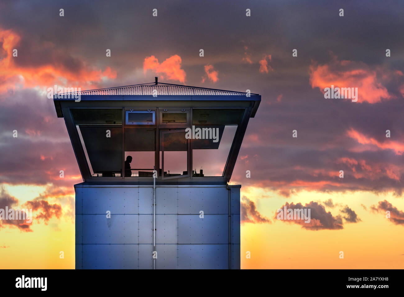 An air traffic control tower with the silhouette of male traffic controller, cloudy weather, Iceland. Stock Photo