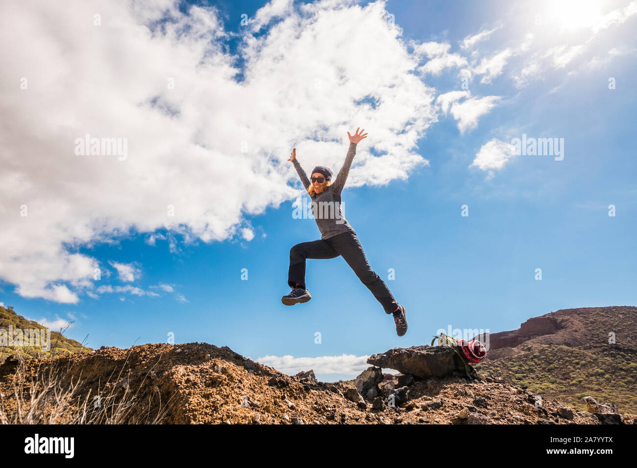 Happy healthy lifestyle woman smile and jump at the mountains having fun in trekking adventure activity - freedom and independence for people in the n Stock Photo