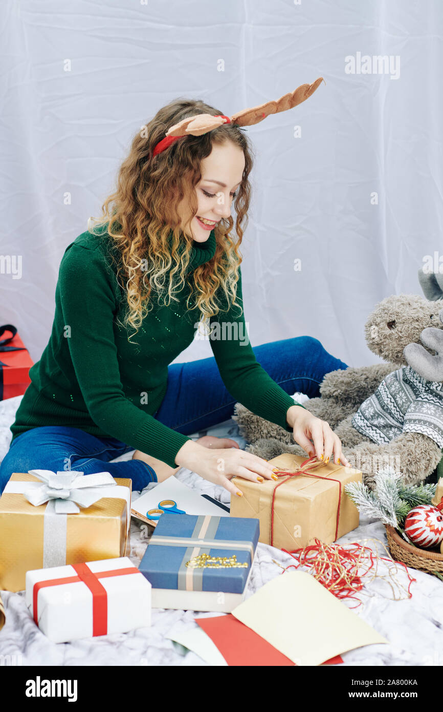 Smiling young pretty woman wrapping various gifs and presents for Christmas  celebration Stock Photo - Alamy