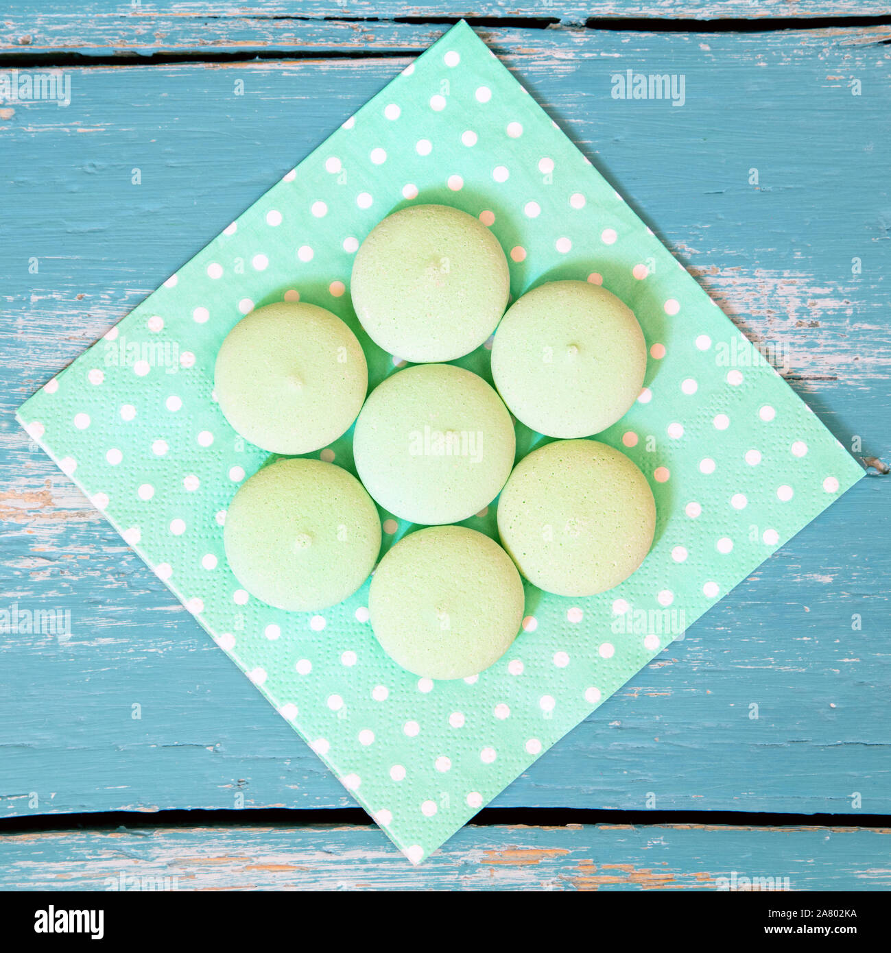 square of green biscuits or cookies on a dotted napkin, blue wooden background Stock Photo