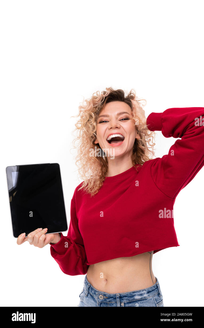 Caucasian girl with curly fair hair holds a tablet and smiles, portrait