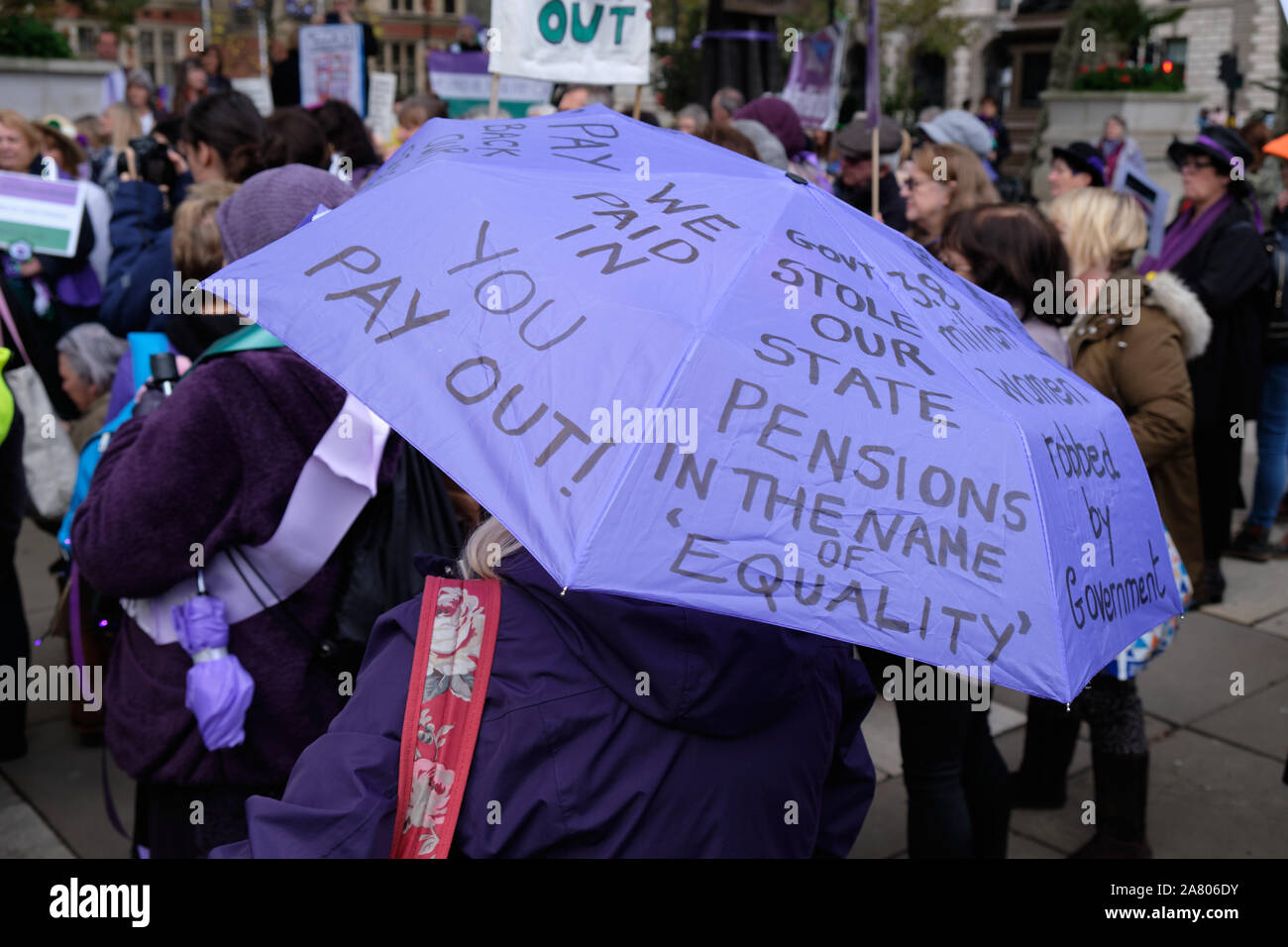 Westminster, London, UK. WASPI (Women Against State Pension Injustice) rally, Purple Umbrella with message Stock Photo