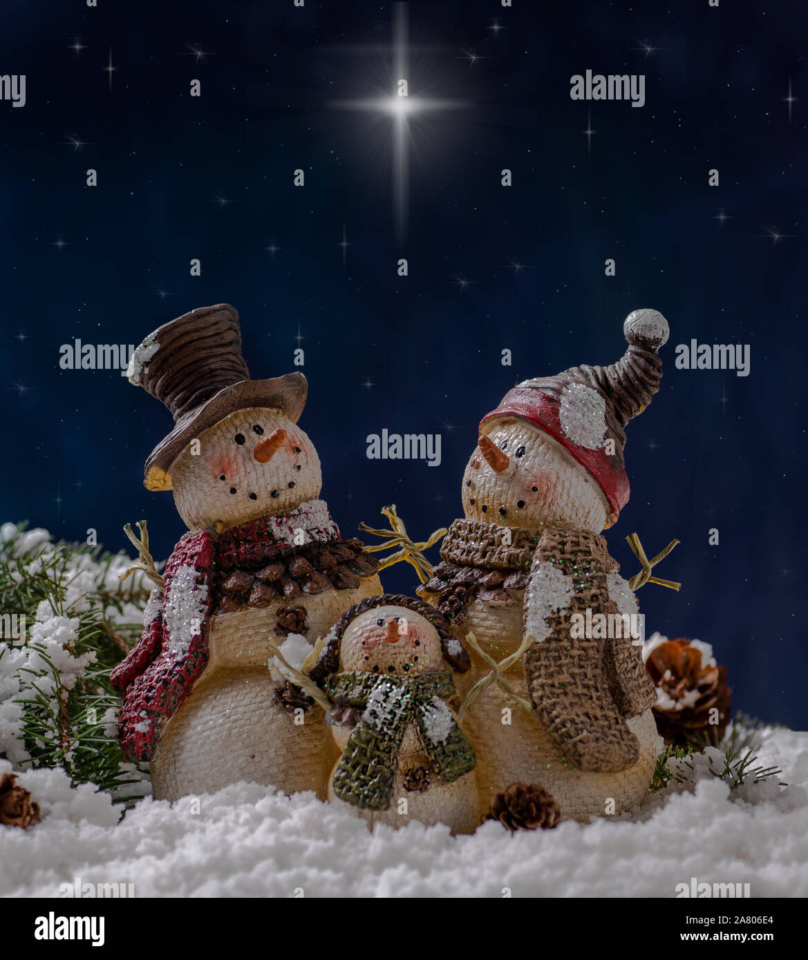 Holiday snowmen figurines on snowy surface against a night sky background with shining stars Stock Photo