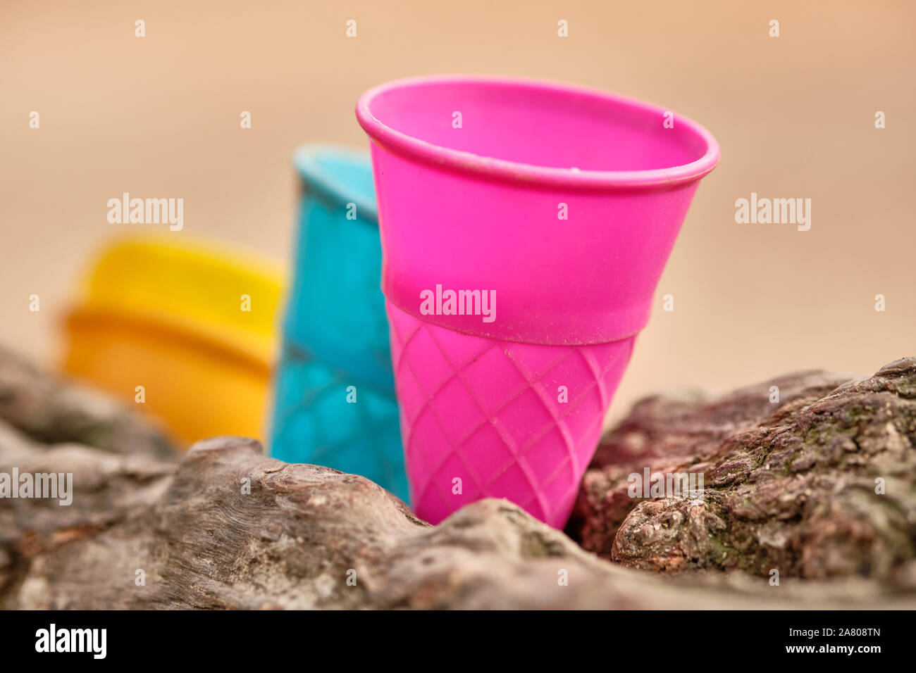 Some colorful outdoor play equipment in form of used plastic ice cream cone inserted between two branches of a tree. Seen in Germany in October. Stock Photo