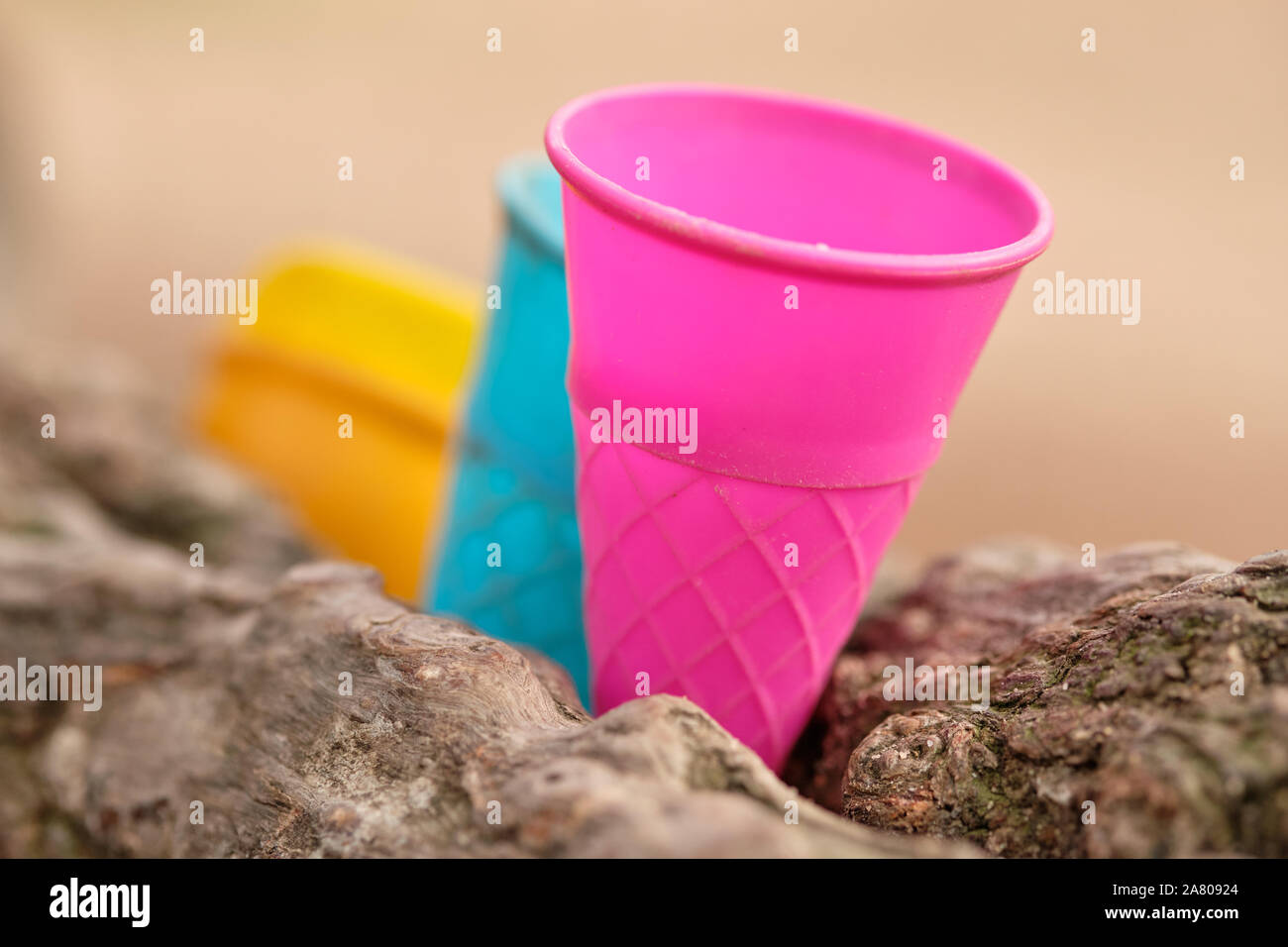 Some colorful outdoor play equipment in form of used plastic ice cream cone inserted between two branches of a tree. Seen in Germany in October. Stock Photo