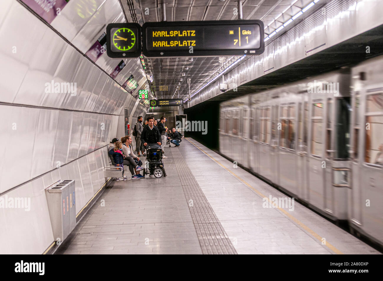 Train enters a metro station in Vienna, Austria Passengers are waiting on the platform Stock Photo