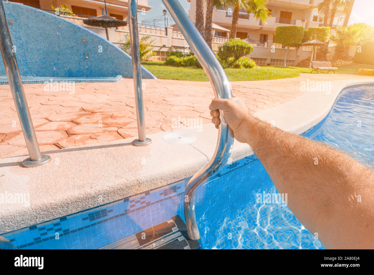 A man holds his hand by the handrail when leaving the pool Stock Photo
