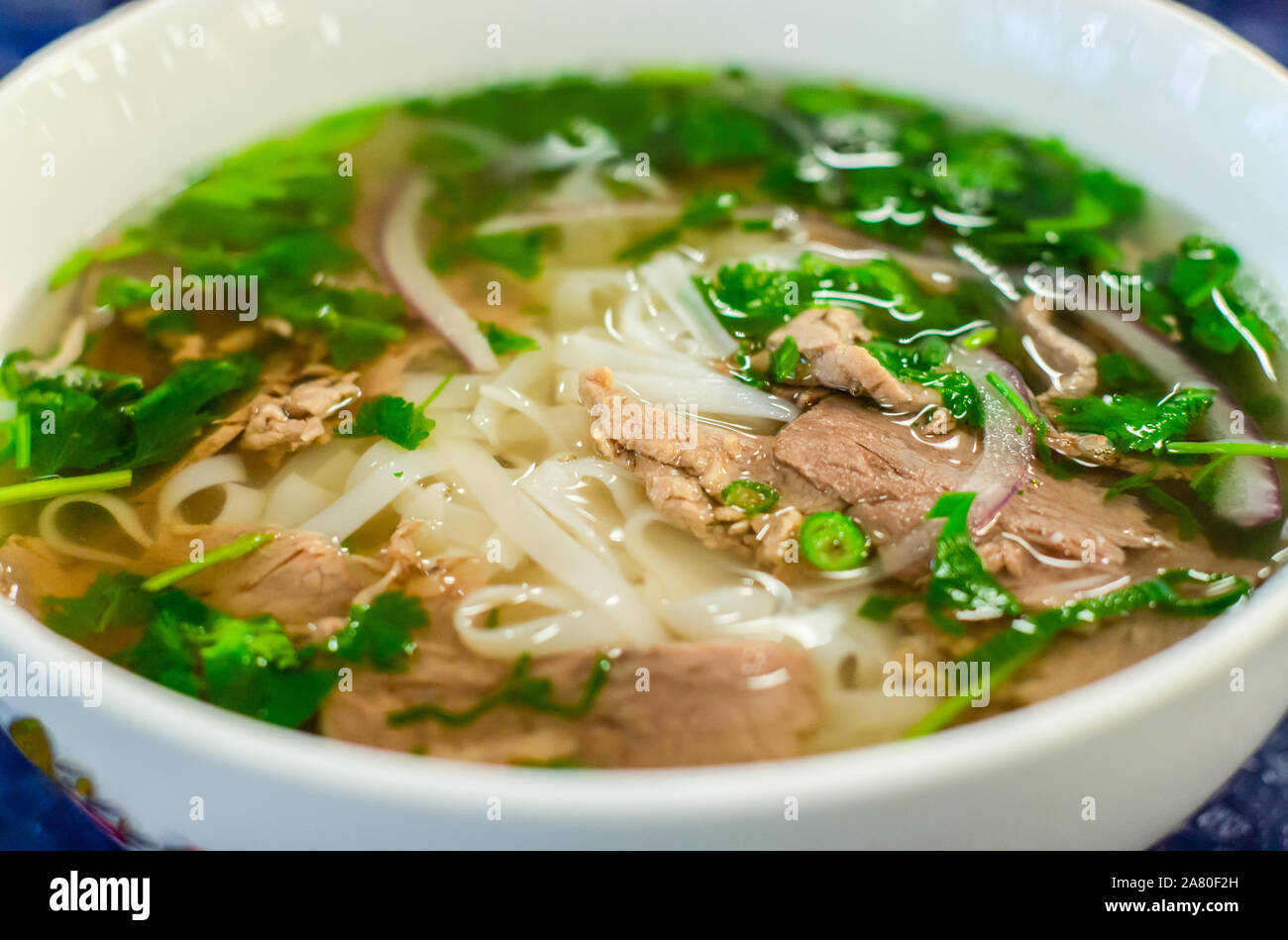 Beef soup pho bo soup, Vietnamese cuisine, first course with noodles and vegetables soup in a white bowl, closeup. Street food Stock Photo