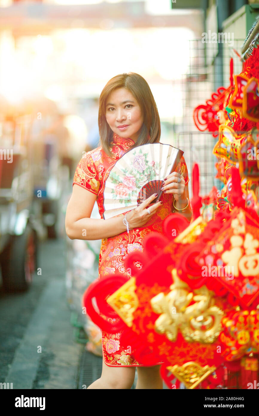asian woman wearing chinese tradition clothes with chinese  bamboo fan toothy smiling face in yaowarat street china town of bangkok thailand Stock Photo