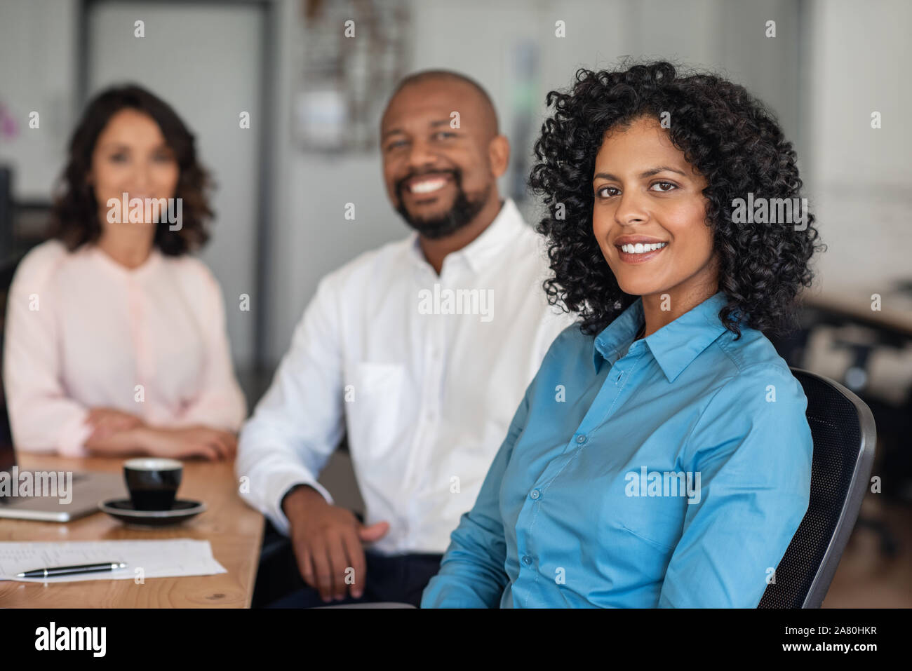 Diverse businesspeople smiling while sitting together at an office table Stock Photo