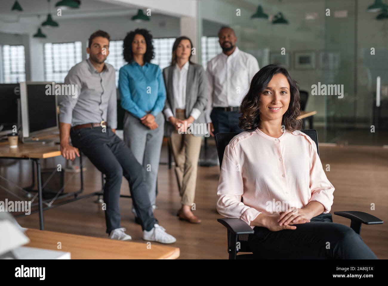 Young businesswoman smiling with colleagues standing in the background Stock Photo