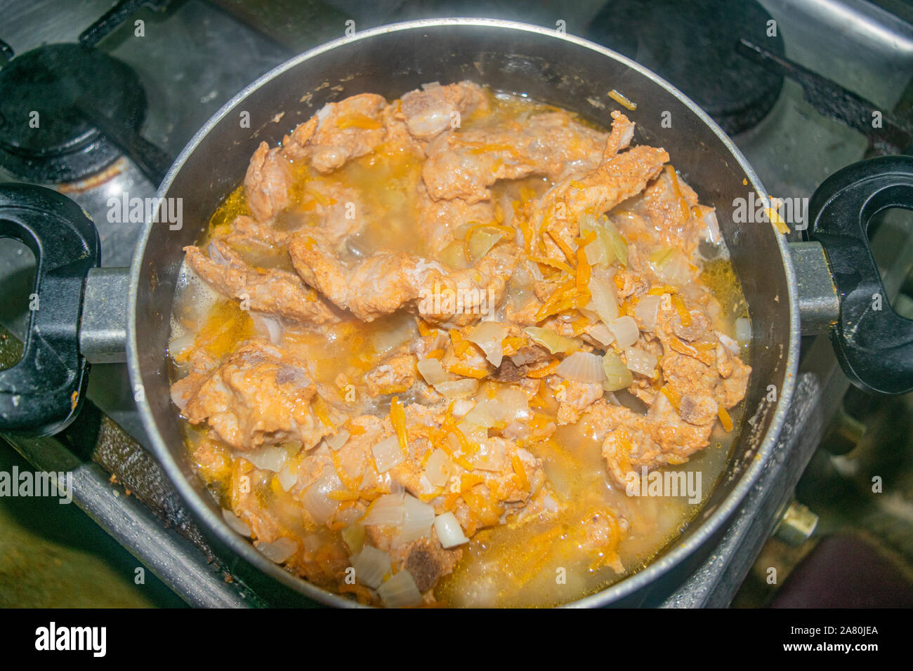 Meat with onions and carrots stewed in a saucepan. Home cooking Stock Photo