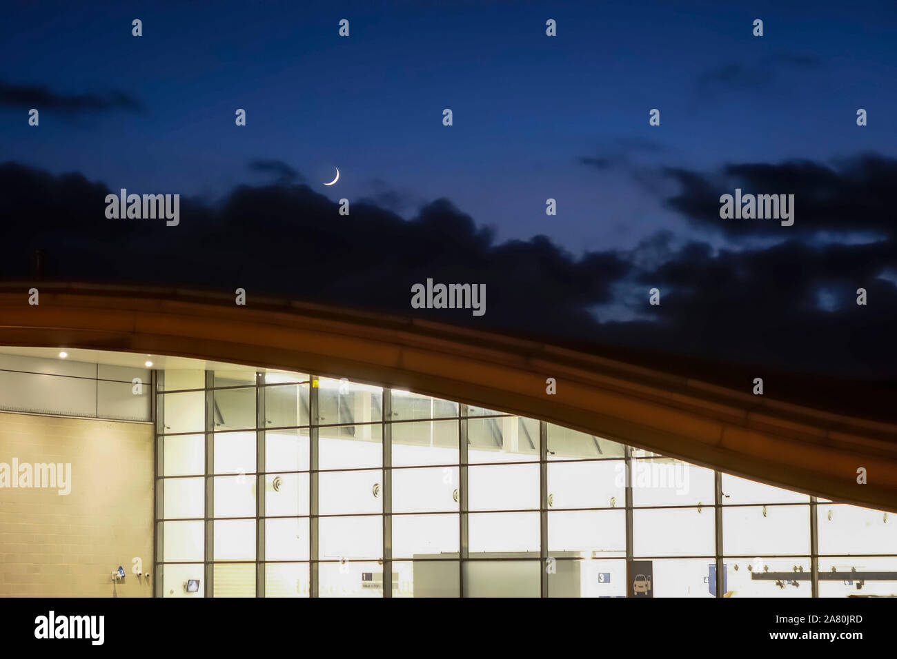 A new moon shining above the curving roof of the Tesco superstore in Ludlow, Shropshire, UK. Designed by MJP Architects in 1997 Stock Photo