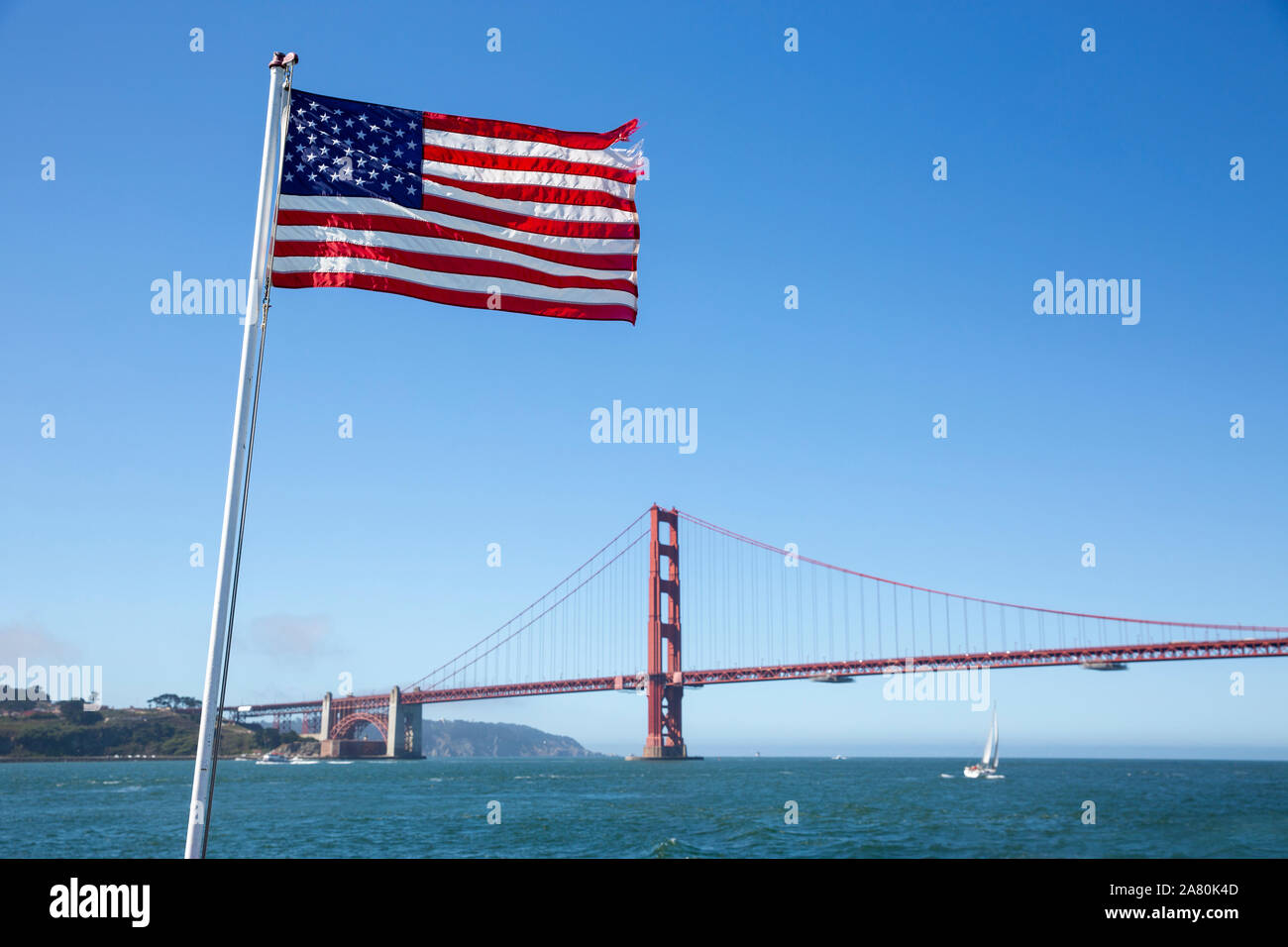 Stars and Stripes flag flying with the Golden Gate Bridge in the background. Stock Photo