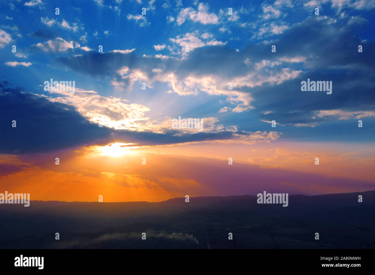 Sun shining through the low clouds of twilight Stock Photo