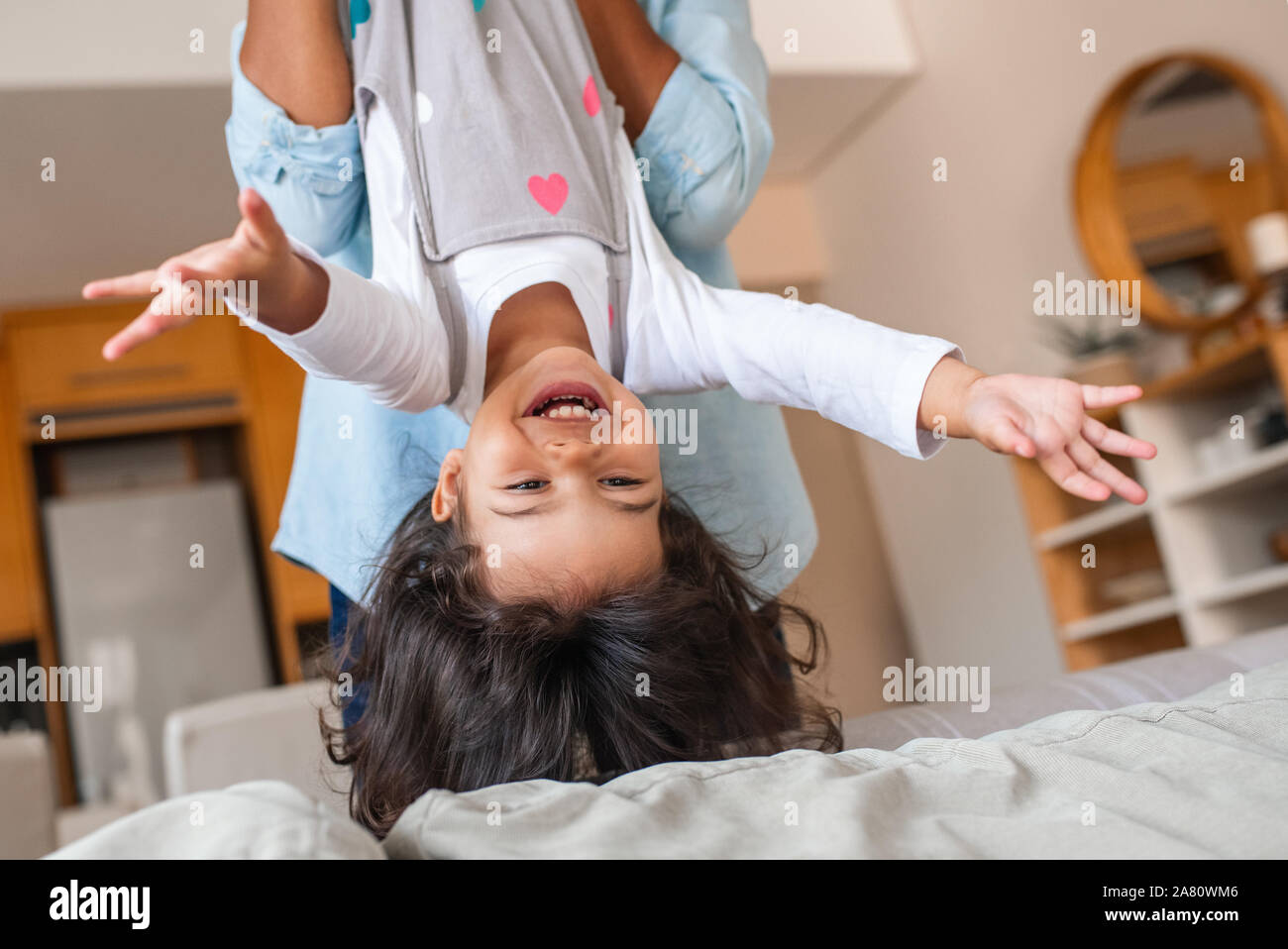 Laughing little daughter being held upside down by her mom Stock Photo