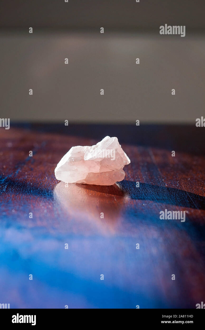 Healing rose crystal or a gemstone on a wooden table. A lovely pink love stone isolated bring good vibes and positive vibrations Stock Photo