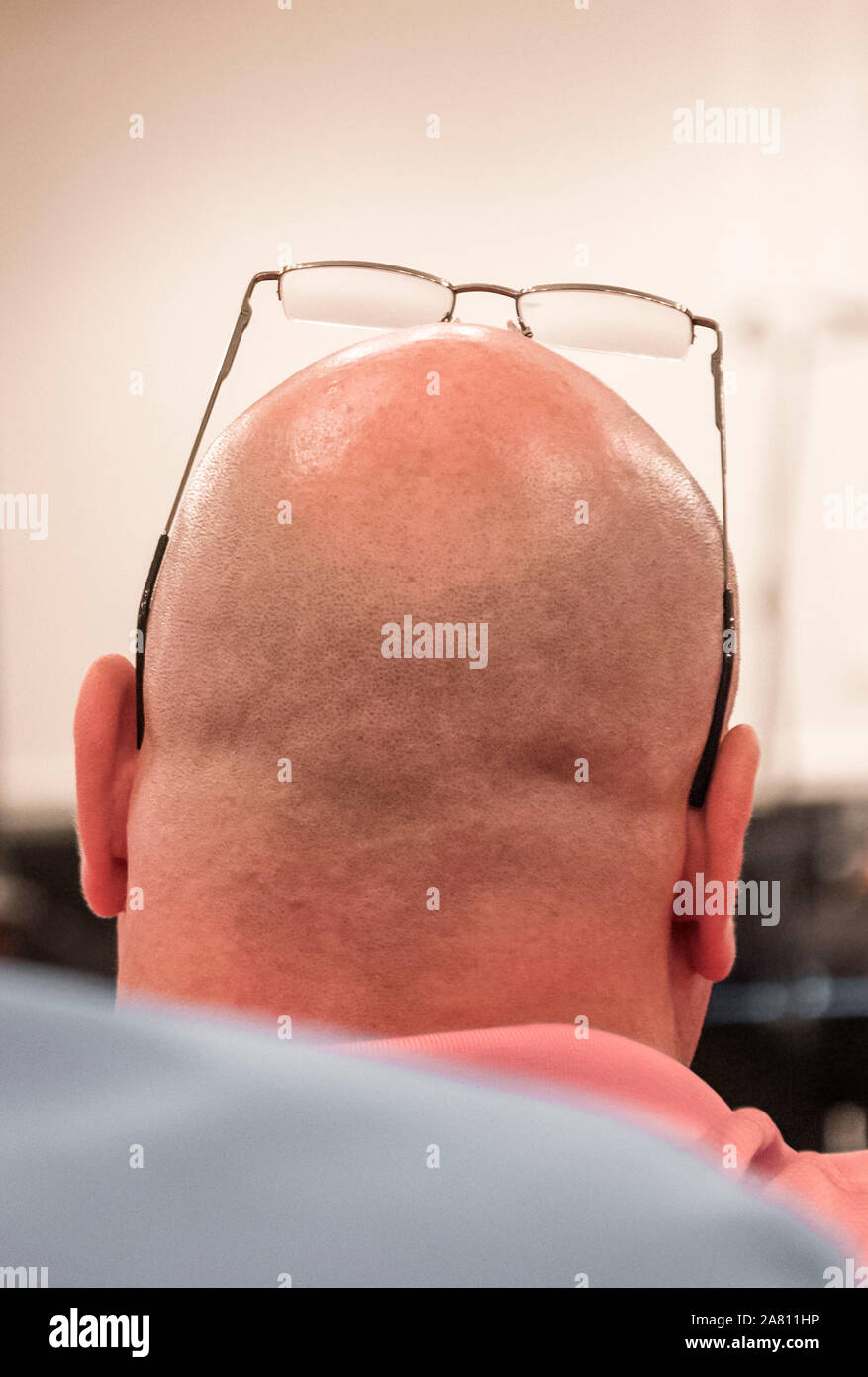 Glasses perched on top of a man's head as he listens to a speaker. Stock Photo