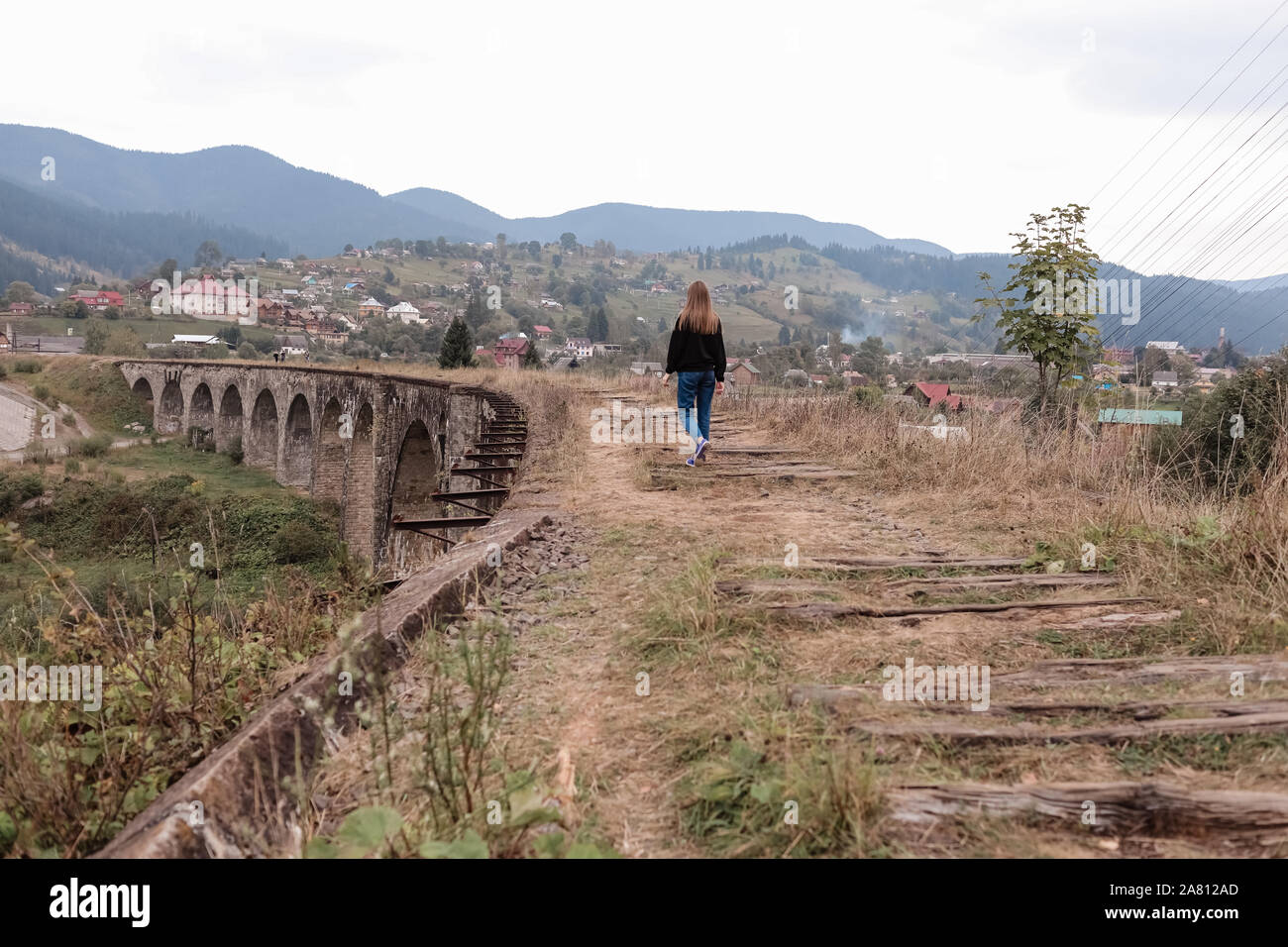 Young tourist girl walks the old railway tracks on the viaduct. Old