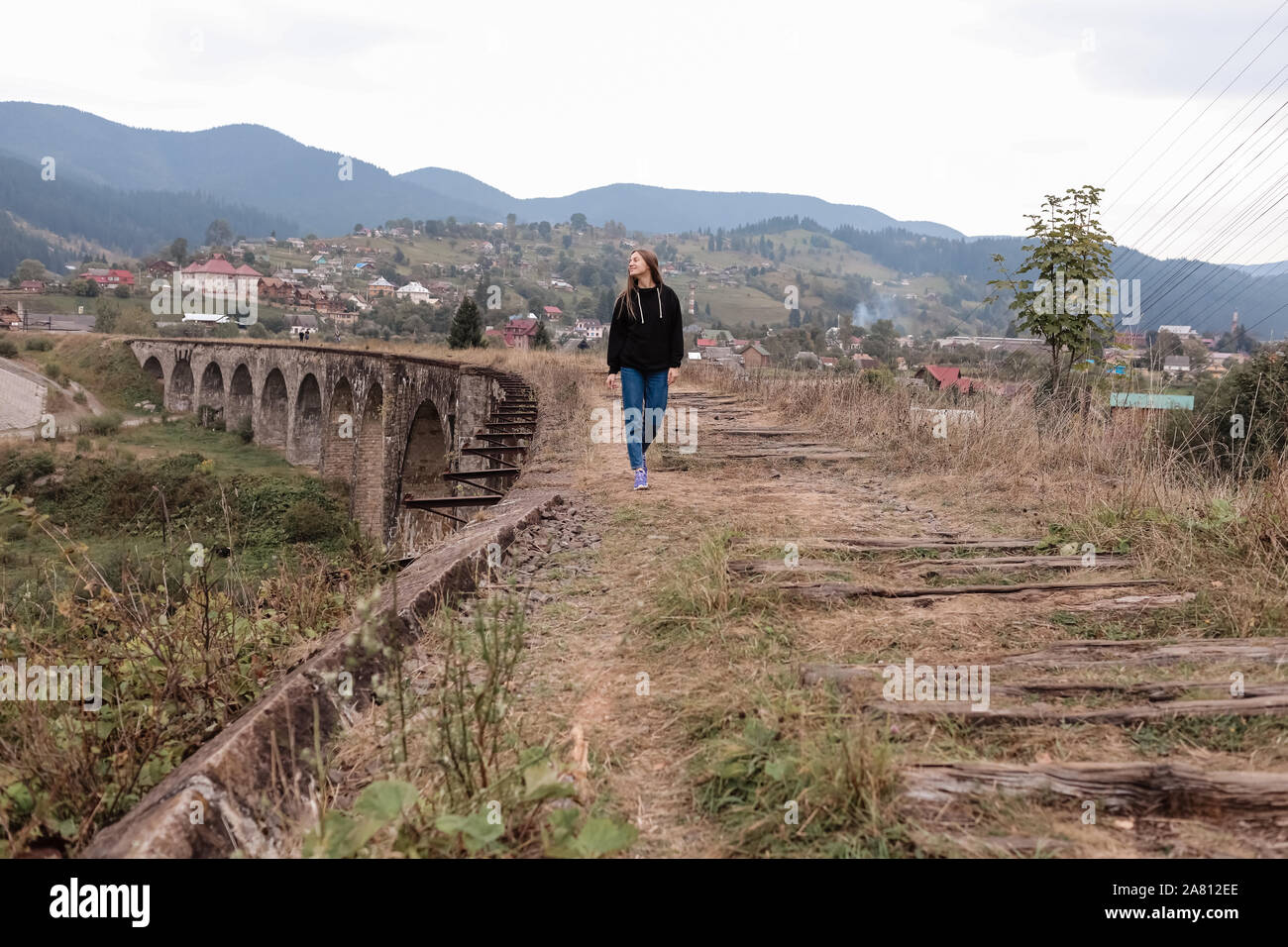 Young tourist girl walks the old railway tracks on the viaduct. Old