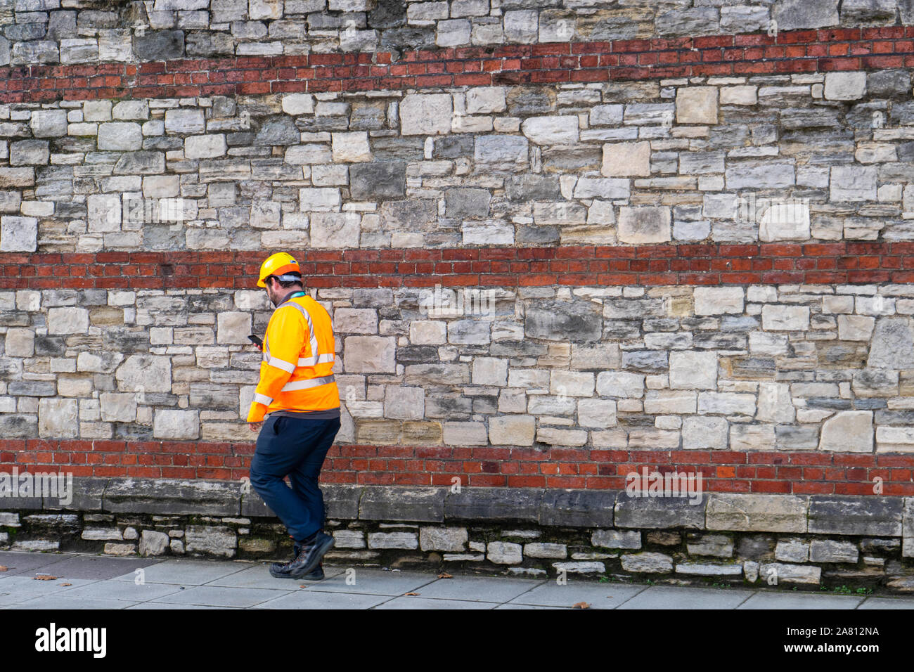 a builder or construction worker wearing high visibility clothing and a hard hat walking Stock Photo