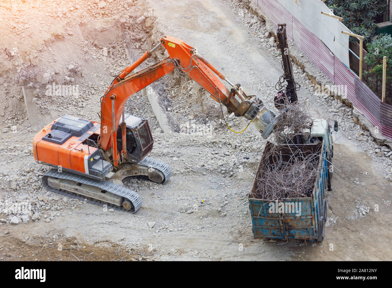 Loading metal reinforcement at a destroyed building with an excavator with a magnet Stock Photo