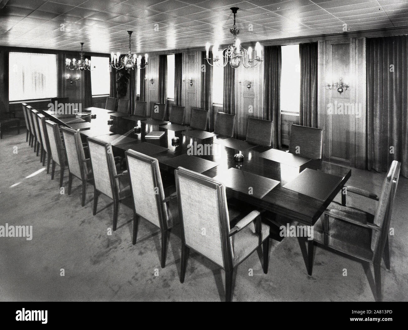 1970s historical, a long table with desk pads and padded chairs in the elegant wood panelled board room of the Swiss Banking Corporation (SBC), Basel, Switzerland. Stock Photo