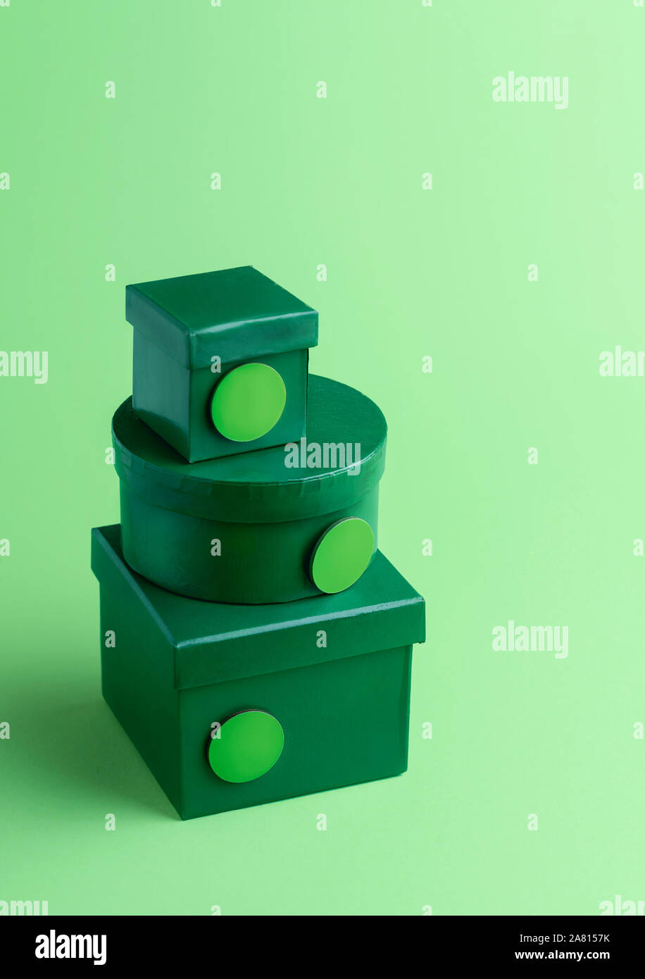 Christmas gift boxes, in a stack on a green background. Xmas gifting themed. Christmas presents with round empty tags. Pile of diverse shaped gifts. Stock Photo