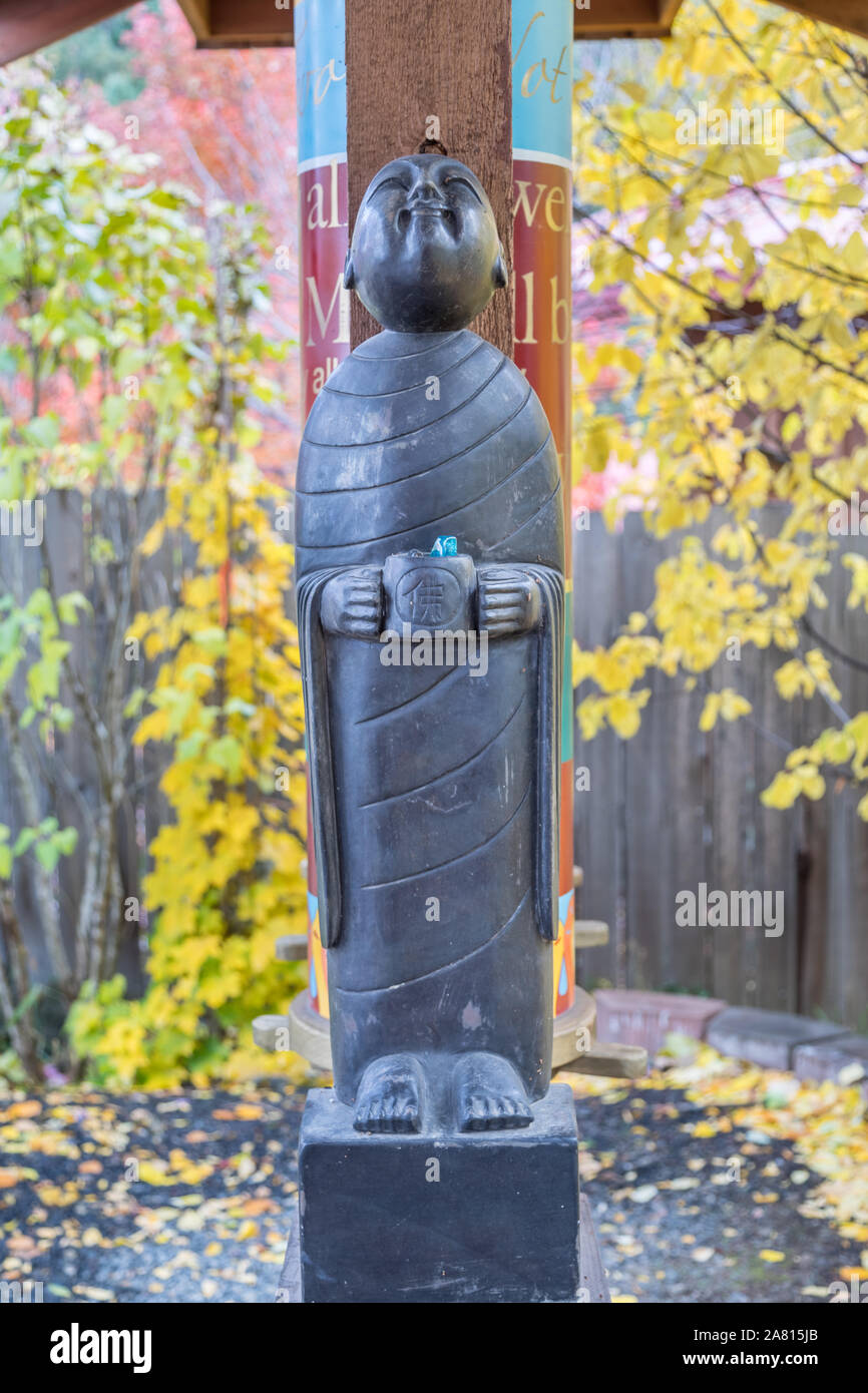 Buddhist Monk statue holding alms bowl looking up with a smile Stock Photo