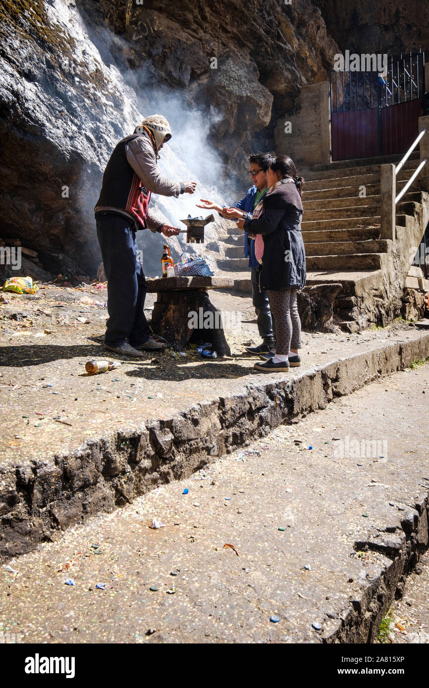 Shaman performing an offering ritual for a local couple at the Cave of the Virgin of Lourdes near Copacabana, Bolivia Stock Photo