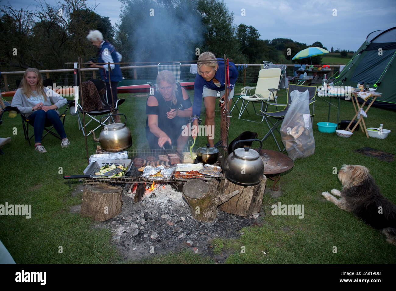Family cooking over camp fire, camp site UK Stock Photo