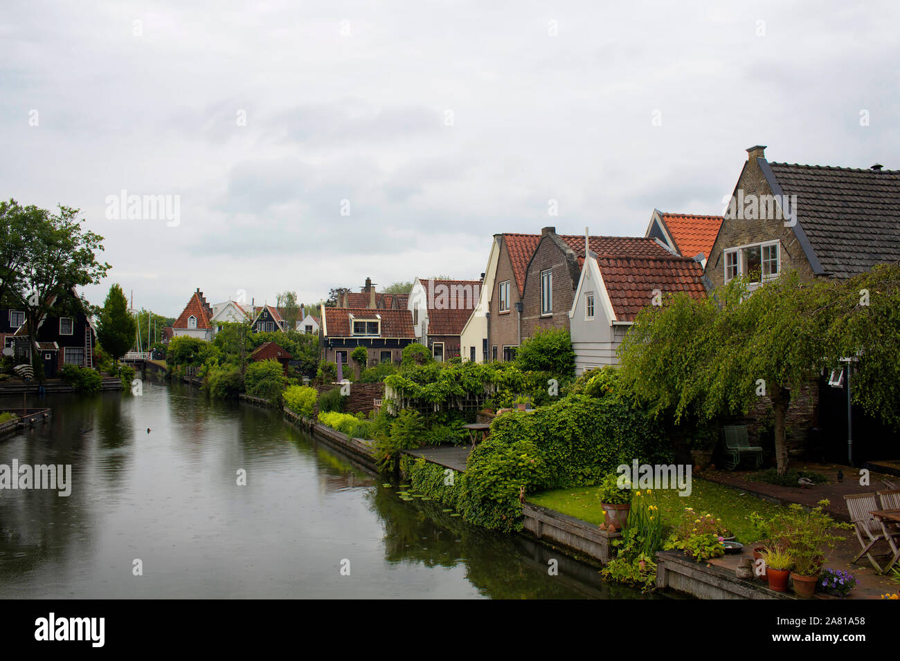 View of traditional houses, trees, plants and canal in Edam. It is a town famous for its semi hard cheese in the northwest Netherlands, in the provinc Stock Photo