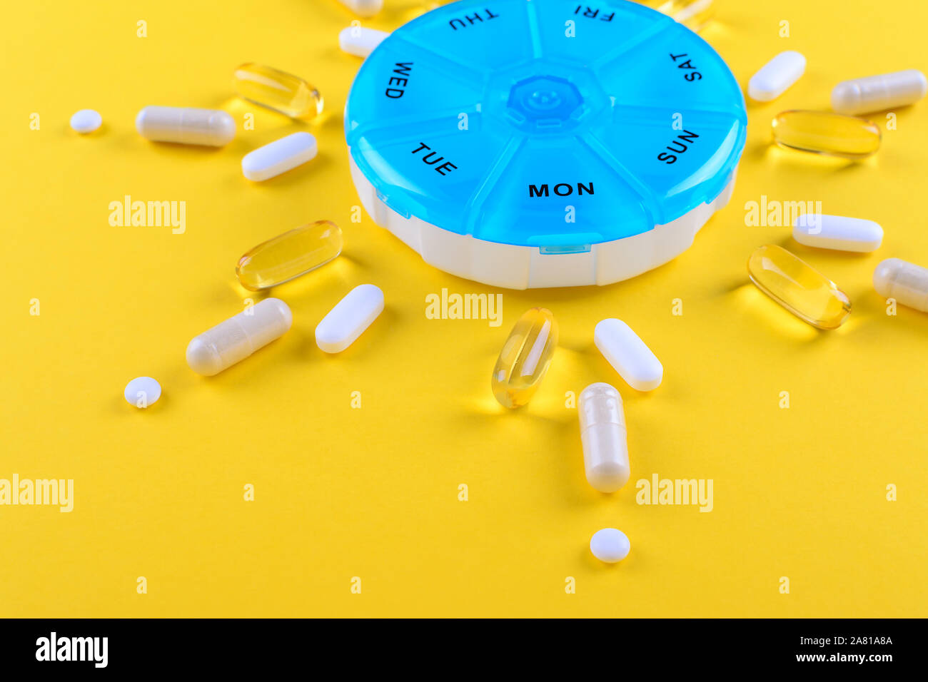 different medicines for one week and a pills box on yellow background Stock Photo