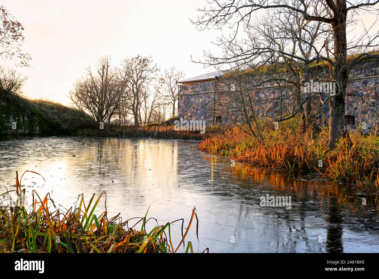 Fortifications of Suomenlinna by a small ice covered pond just before sunset. Suomenlinna is a UNESCO World Heritage site. Helsinki, Finland. Oct 2019 Stock Photo