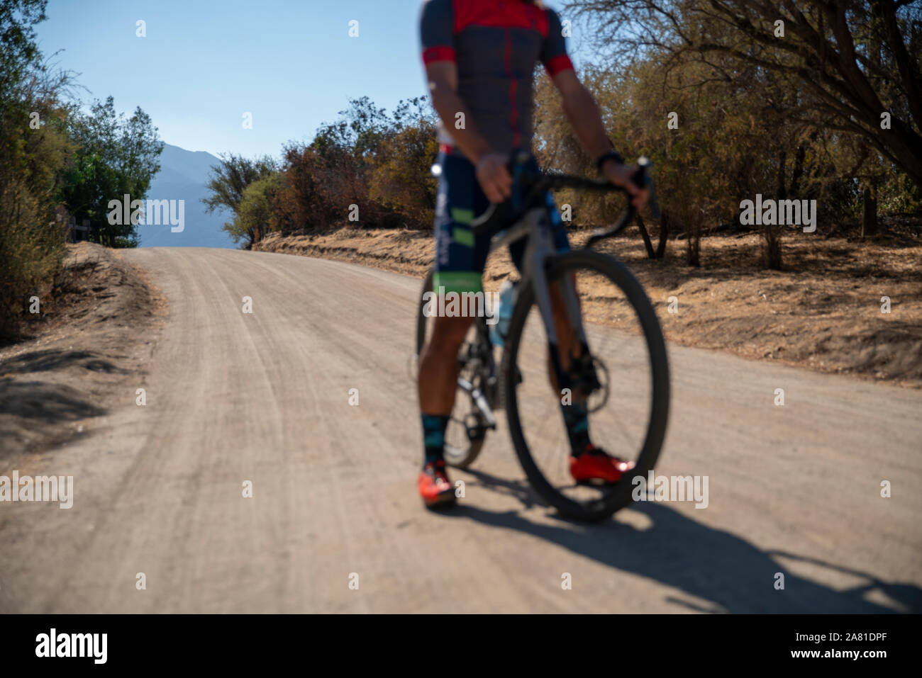 Male cyclist standing on a dirt road with his bike. Stock Photo