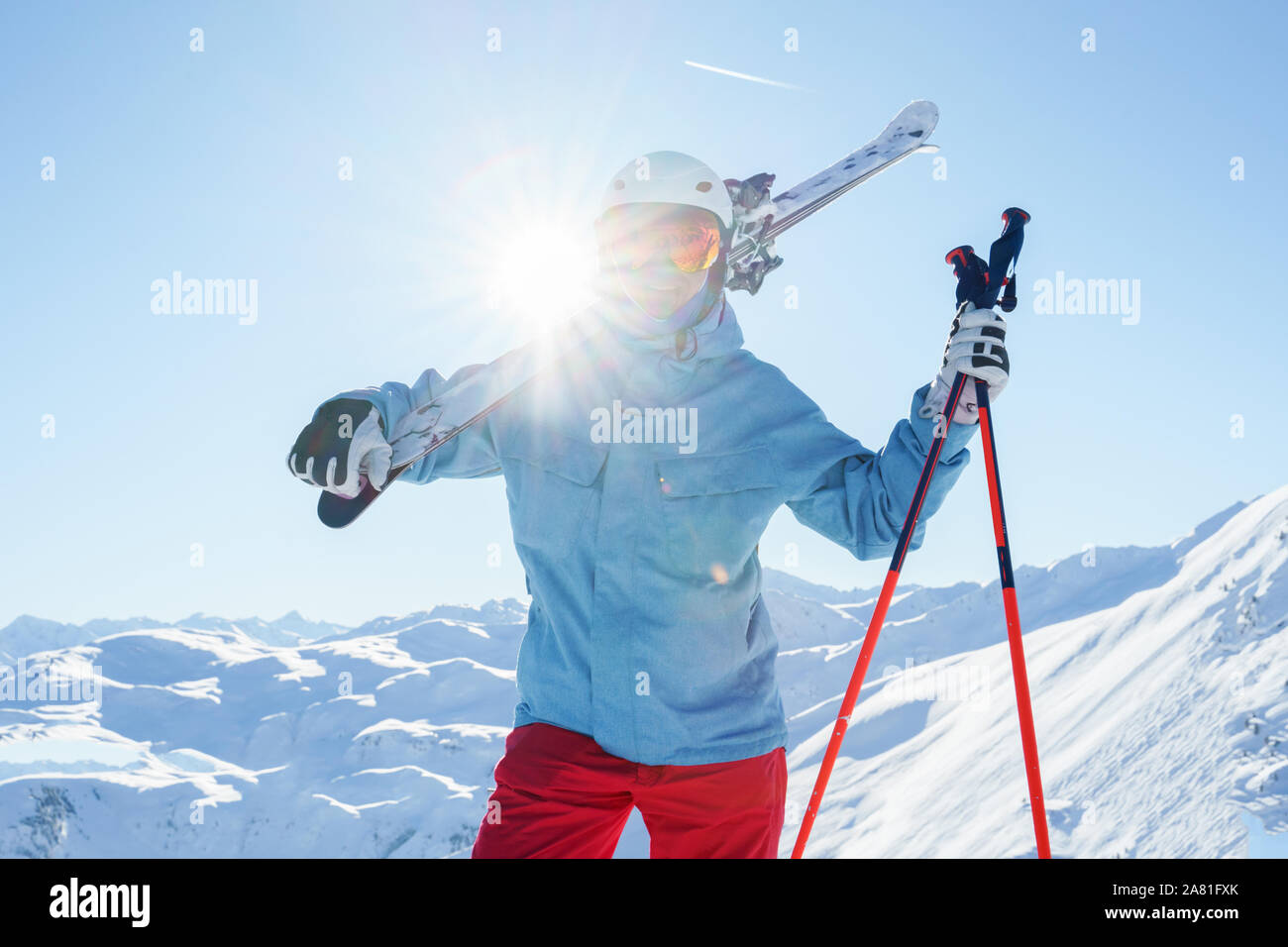 Photo of athlete in helmet and mask with skis on his shoulder at winter