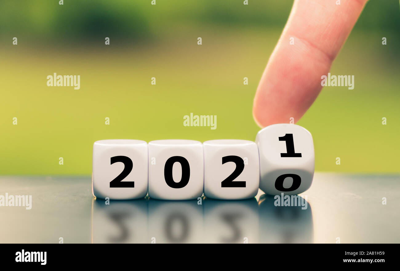 Hand turns a dice and changes the year '2020' to '2021'. Stock Photo