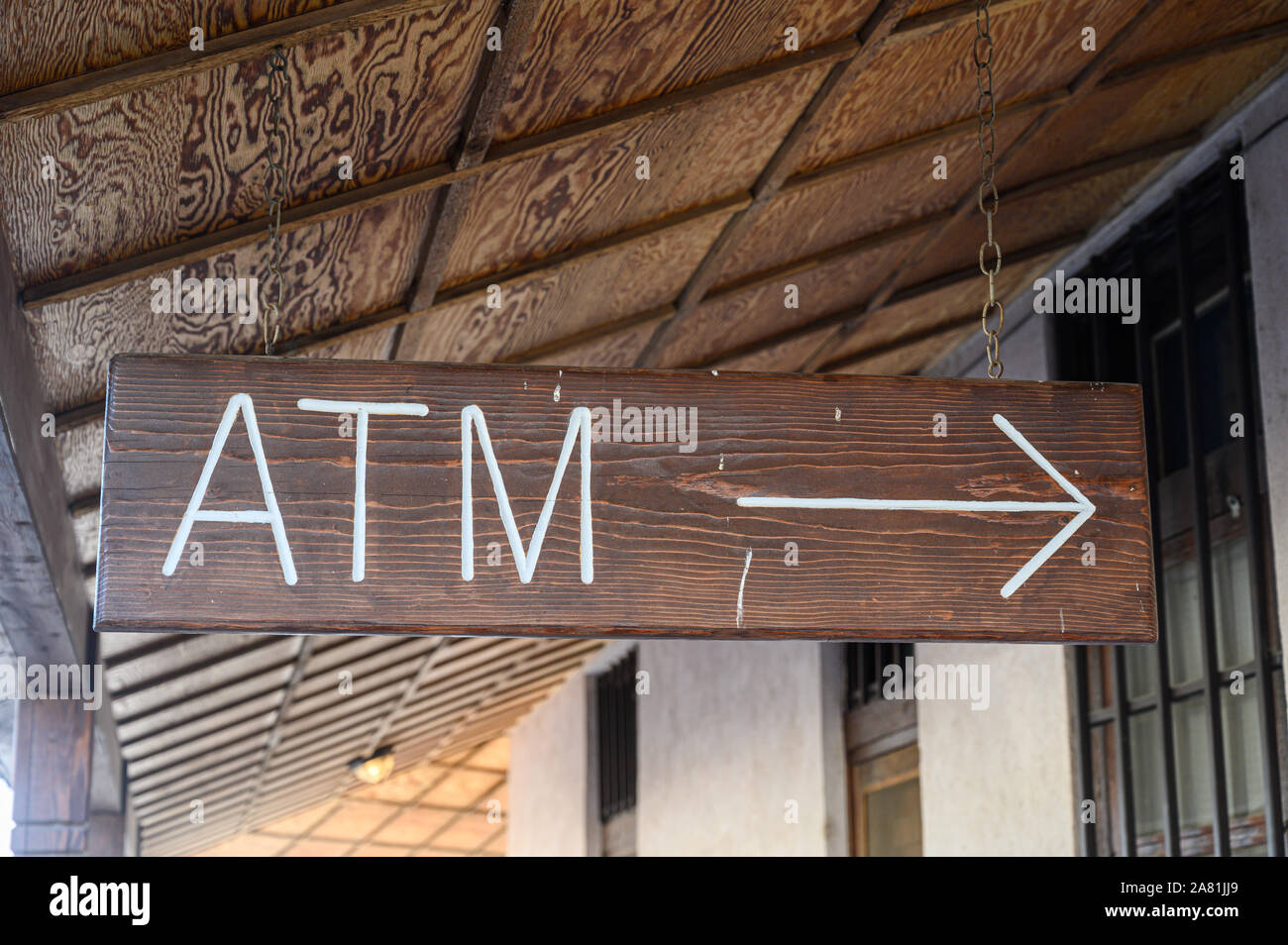A wooden sign points to an ATM machine Stock Photo