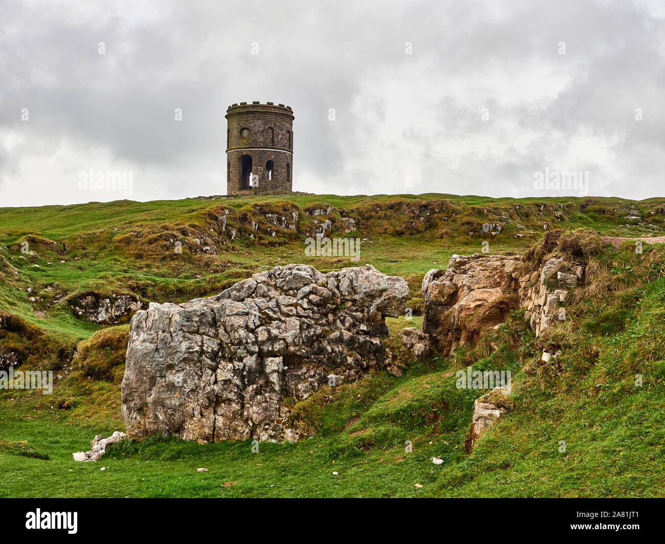 A view of Solomans Temple or Grinlow Tower in the Peak District with a stone wall in the foreground near the town of Buxton in Derbyshire, UK Stock Photo