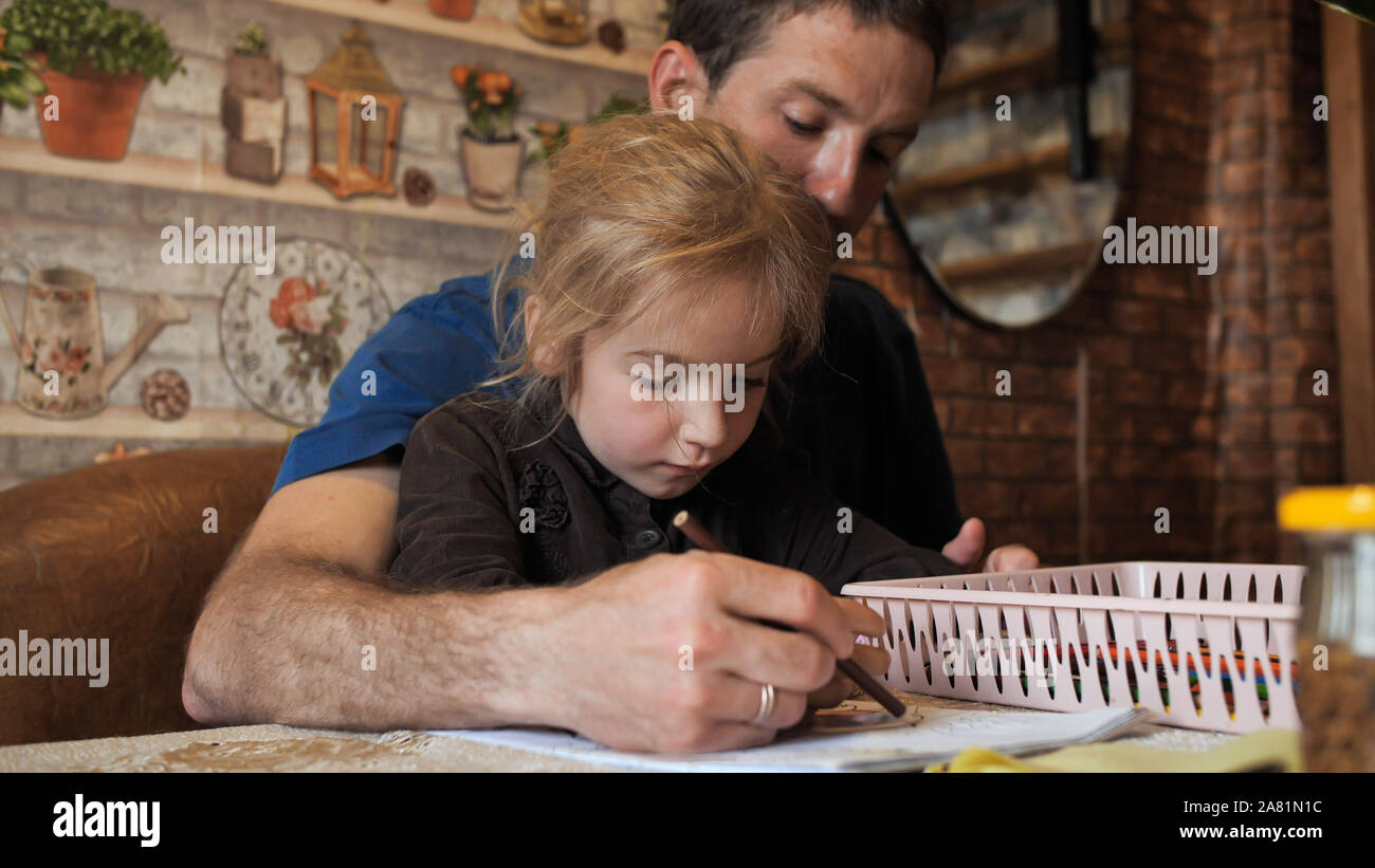 A father helps his daughter draw a drawing Stock Photo - Alamy