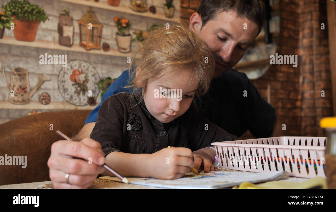 A father helps his daughter draw a drawing Stock Photo - Alamy