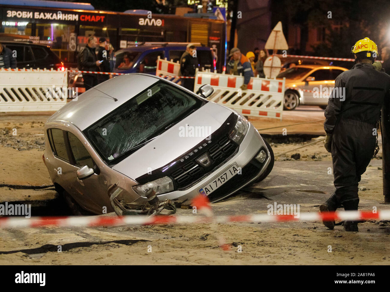A car is seen in a hole of a collapsed road during a pipeline accident in central Kiev.As a result of damage of the trunk pipeline on a road in downtown of Kiev two cars fell into the damage zone, the drivers were not injured, reports the site of the Kiev city state administration. Stock Photo