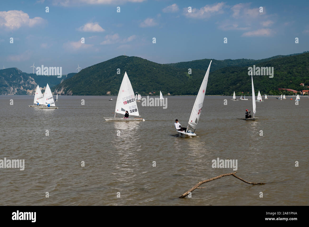Sunny morning view of restless wather and lots of windsurfing seaboats  on the river Danube, with mountines in the background and cloudy sky high abov Stock Photo