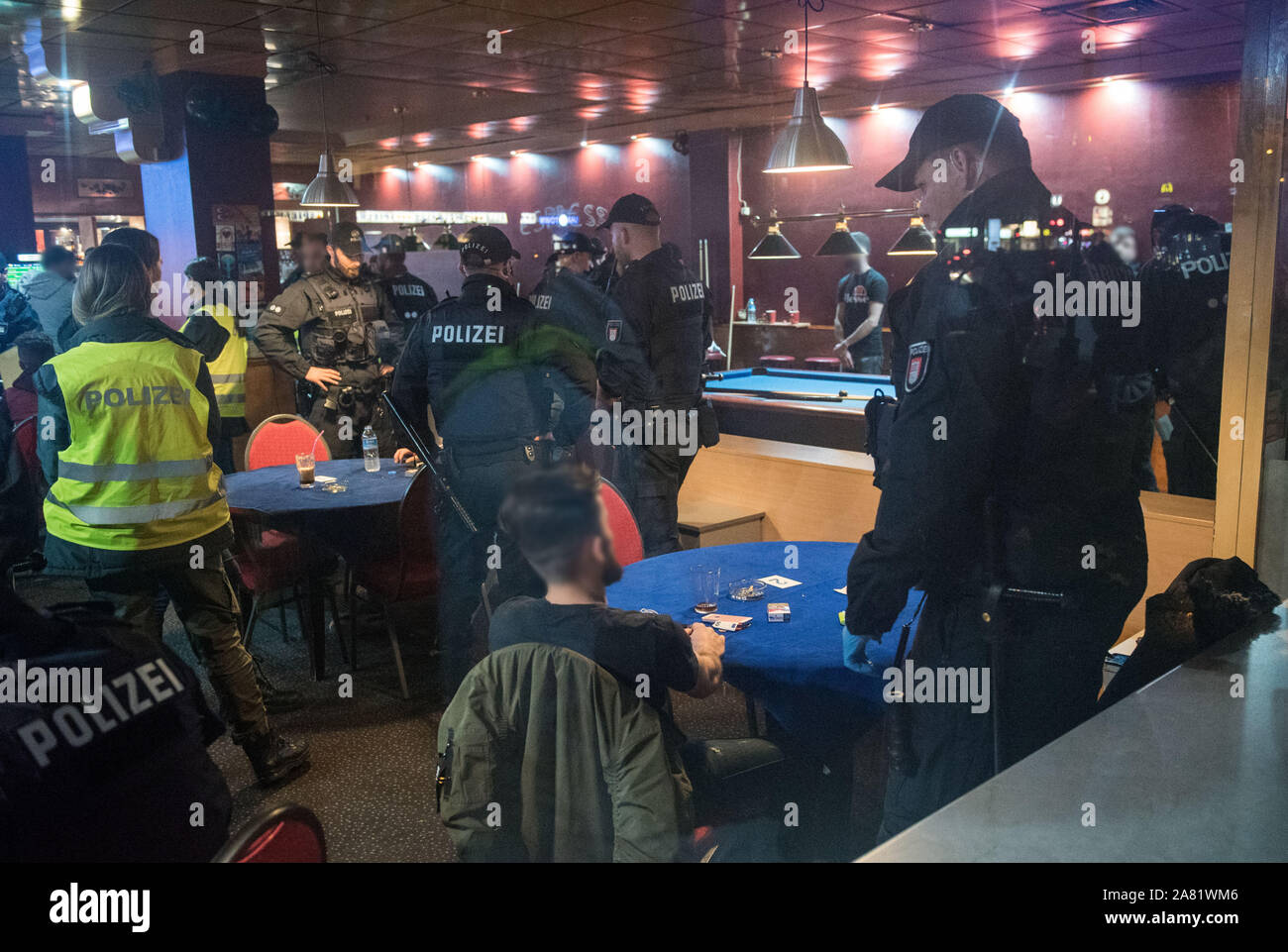 Hamburg, Germany. 05th Nov, 2019. Police officers stand in a sports bar in  the Billstedt district and check the personal details of the guests  (admission through a window). In the evening, the