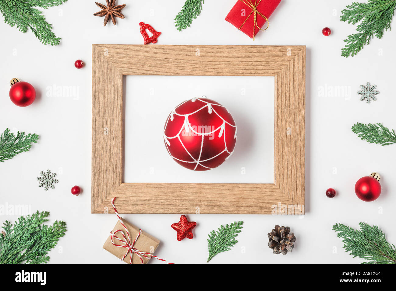 Christmas or Happy New Year composition. Red ball in picture frame with fir tree branches, red decorations and gift boxes on white background. top vie Stock Photo