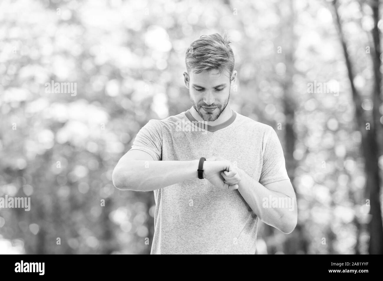 Smart fitness. Fit athlete tracking his fitness activity with sports watch. Handsome athlete using fitness tracker during training outdoor. Monitoring his health with the best fitness device. Stock Photo