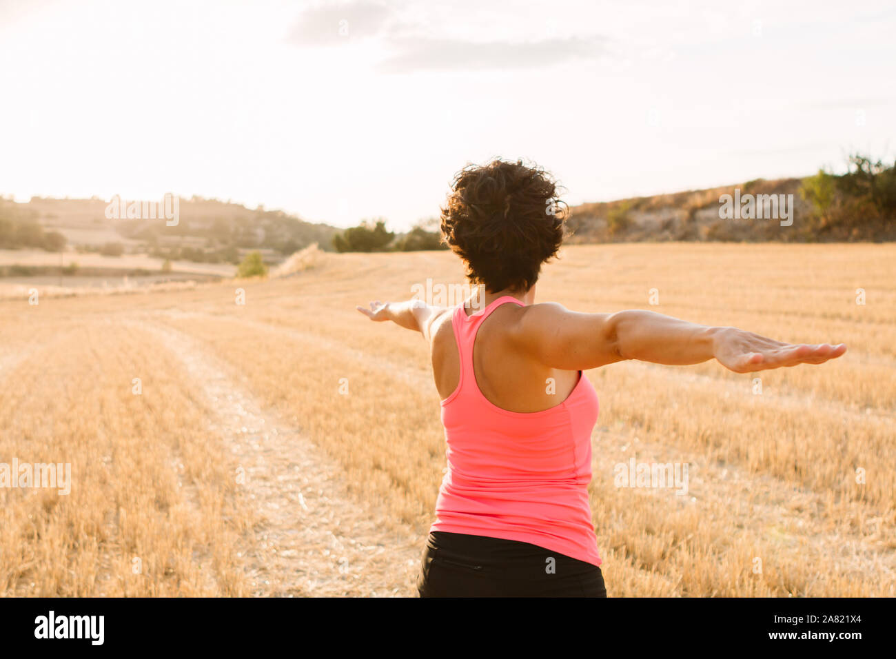 Shot of young curly woman doing yoga outdoors at sunset Stock Photo